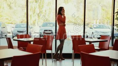 女人在咖啡馆的窗户附近打电话。 全面增长